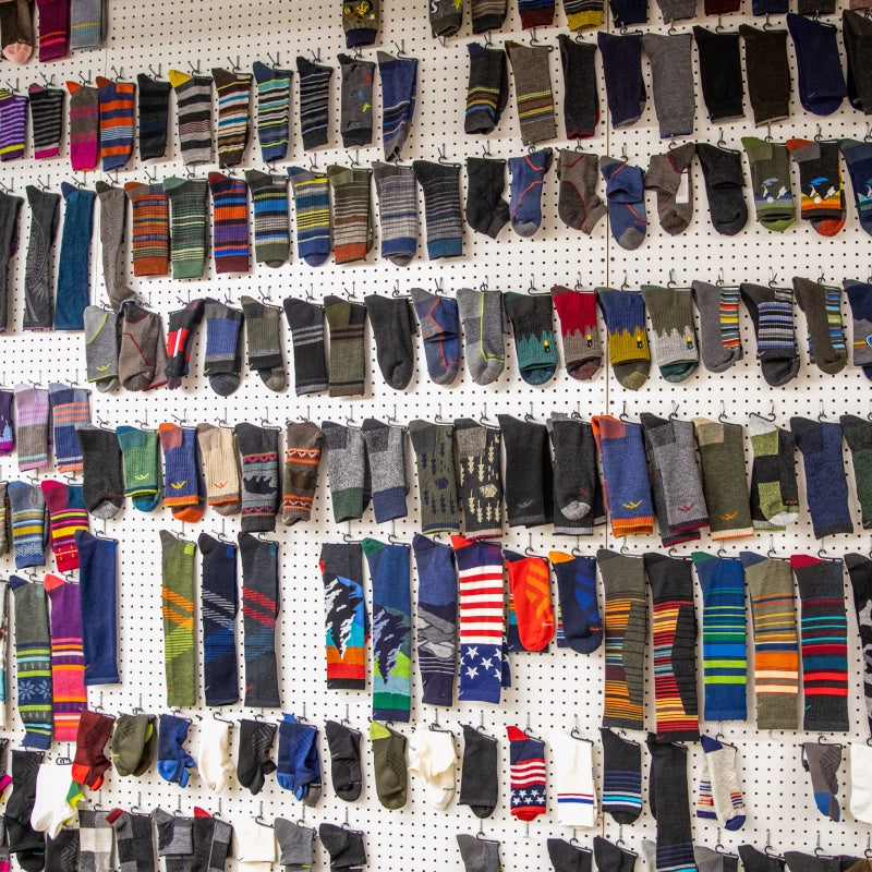Many styles of Darn Tough socks hanging on a wall in the mill
