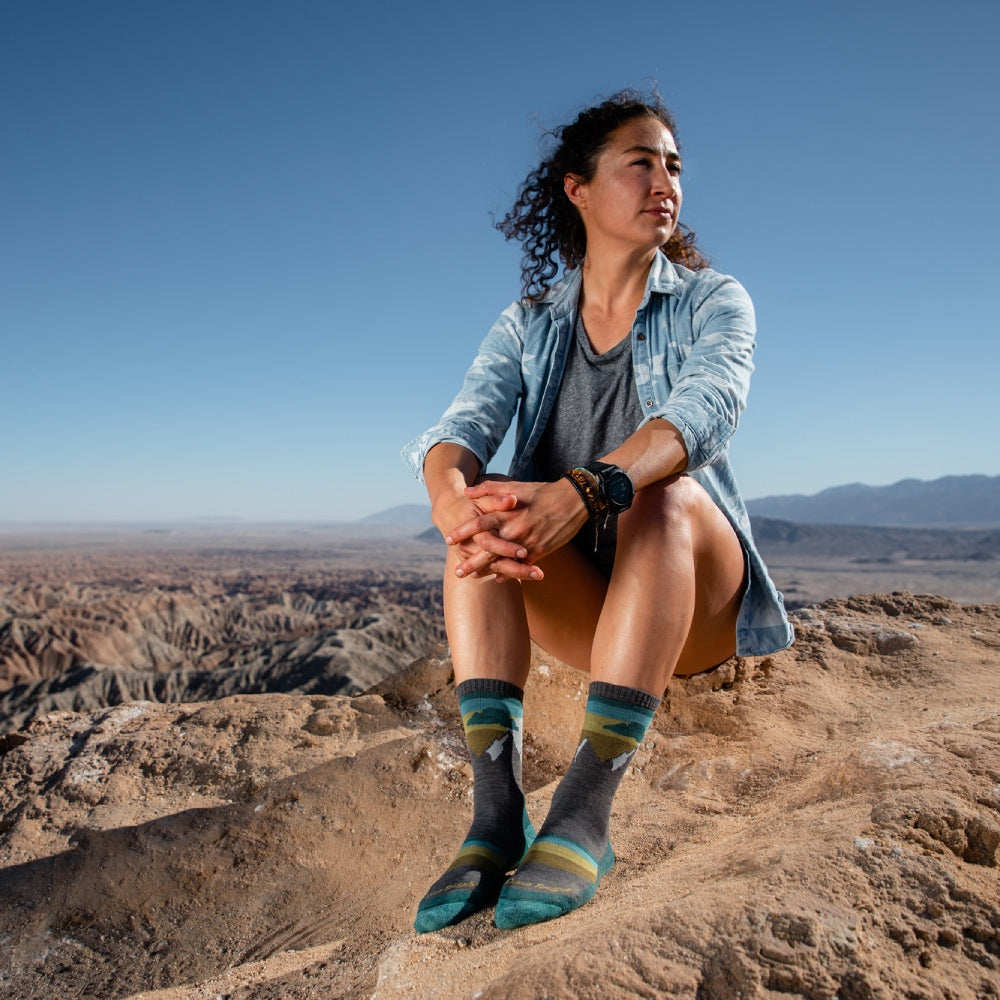 Lady hiker seated on summit wearing Darn Tough women's hiking socks
