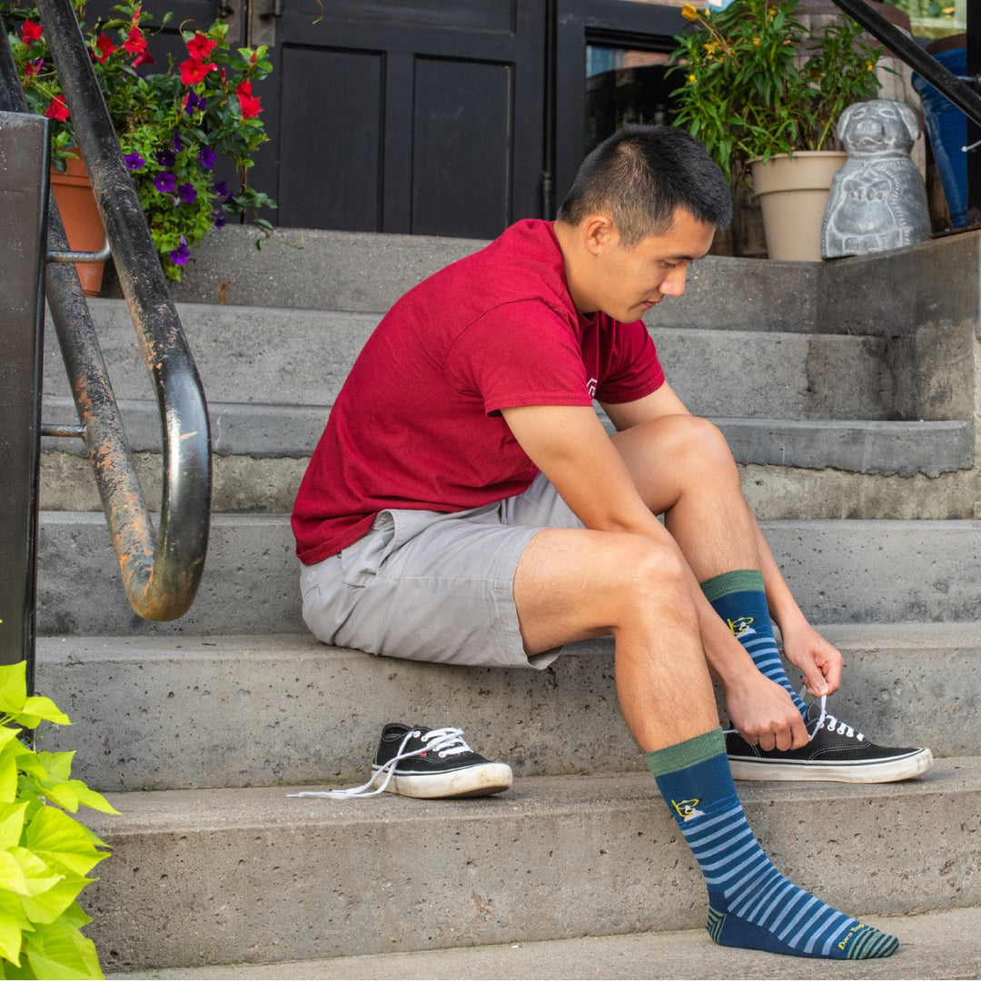 Man seated on steps putting on converse and merino wool socks for walking