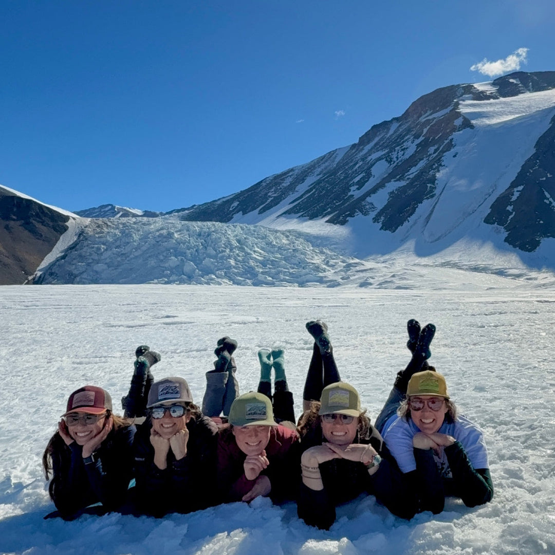The research team at Antarctica laying on a glacier wearing socks with their feet in the air