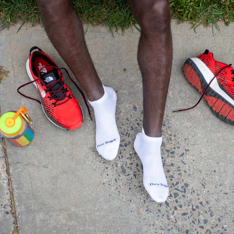 Man sitting with water bottle, running shoes and wearing Darn Tough Coolmax socks