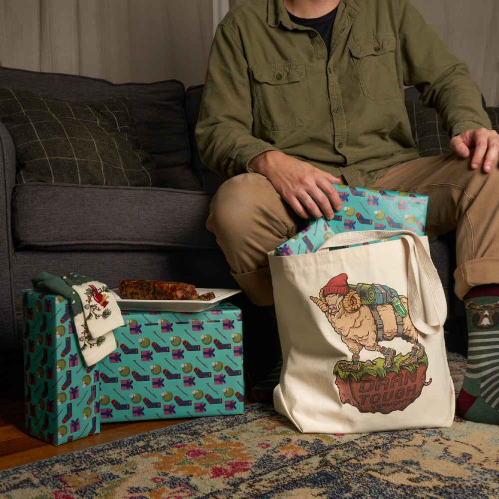 Person unpacking nicely wrapped socks and gifts from a Darn Tough tote bag