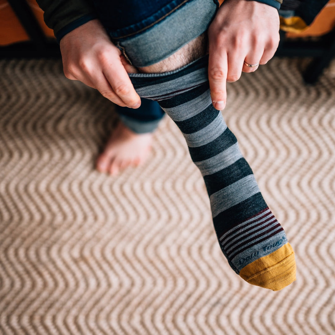 Man pulling a single sock onto his foot, wondering what to do with single socks