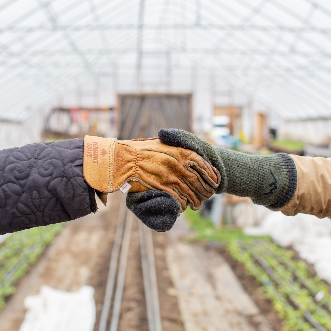 A glove-clad hand shaking hands with a sock-clad hand