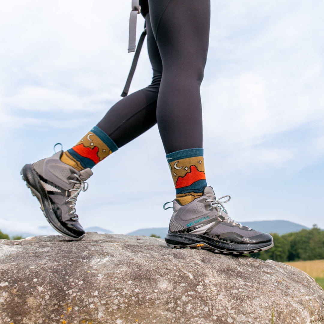 Hiker walking on top of a large boulder wearing micro crew hiking socks.