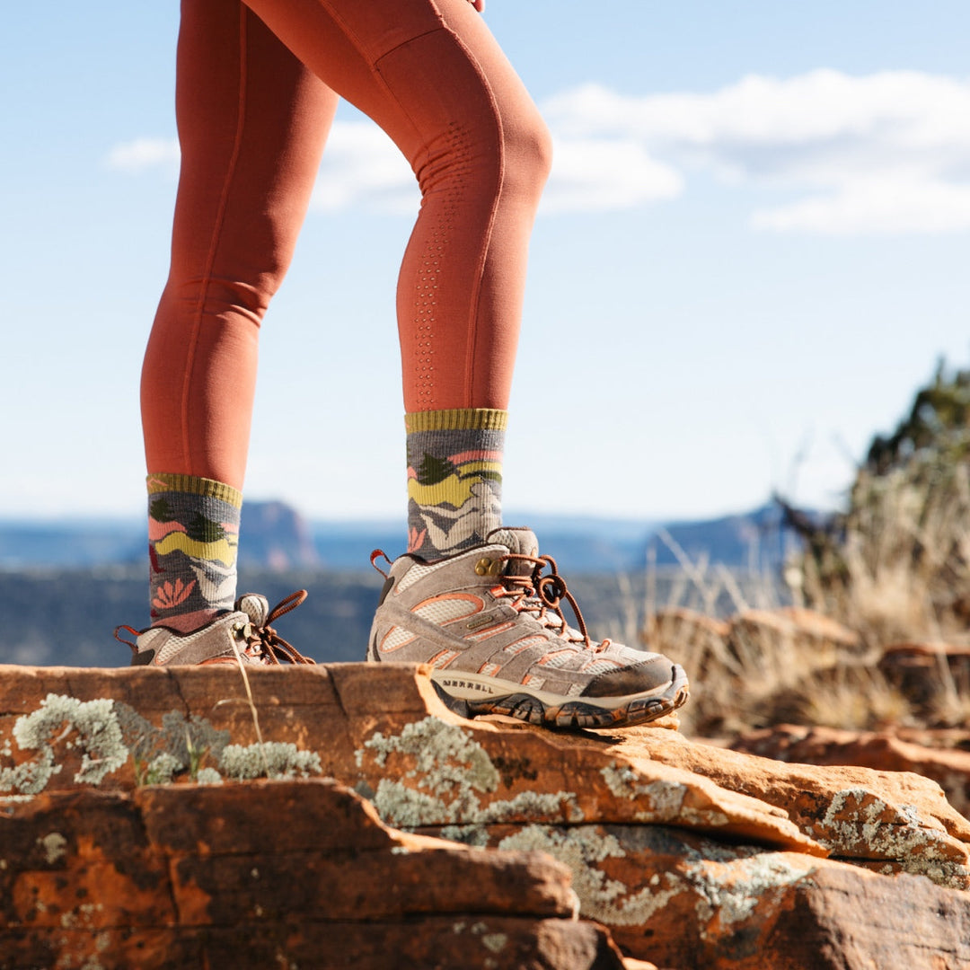 Feet posed on the summit wearing hiking boots and the Trailblazer, women-designed socks