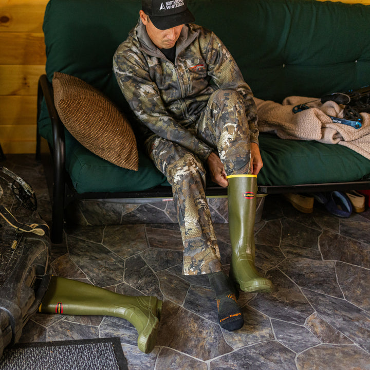 model sitting on couch putting on boots wearing the 2108 Forest