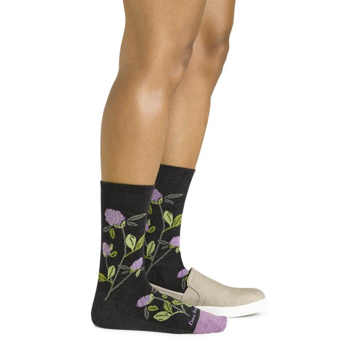 Side shot of model wearing the women's blossom crew lifestyle socks in charcoal with a tan shoe on her left foot