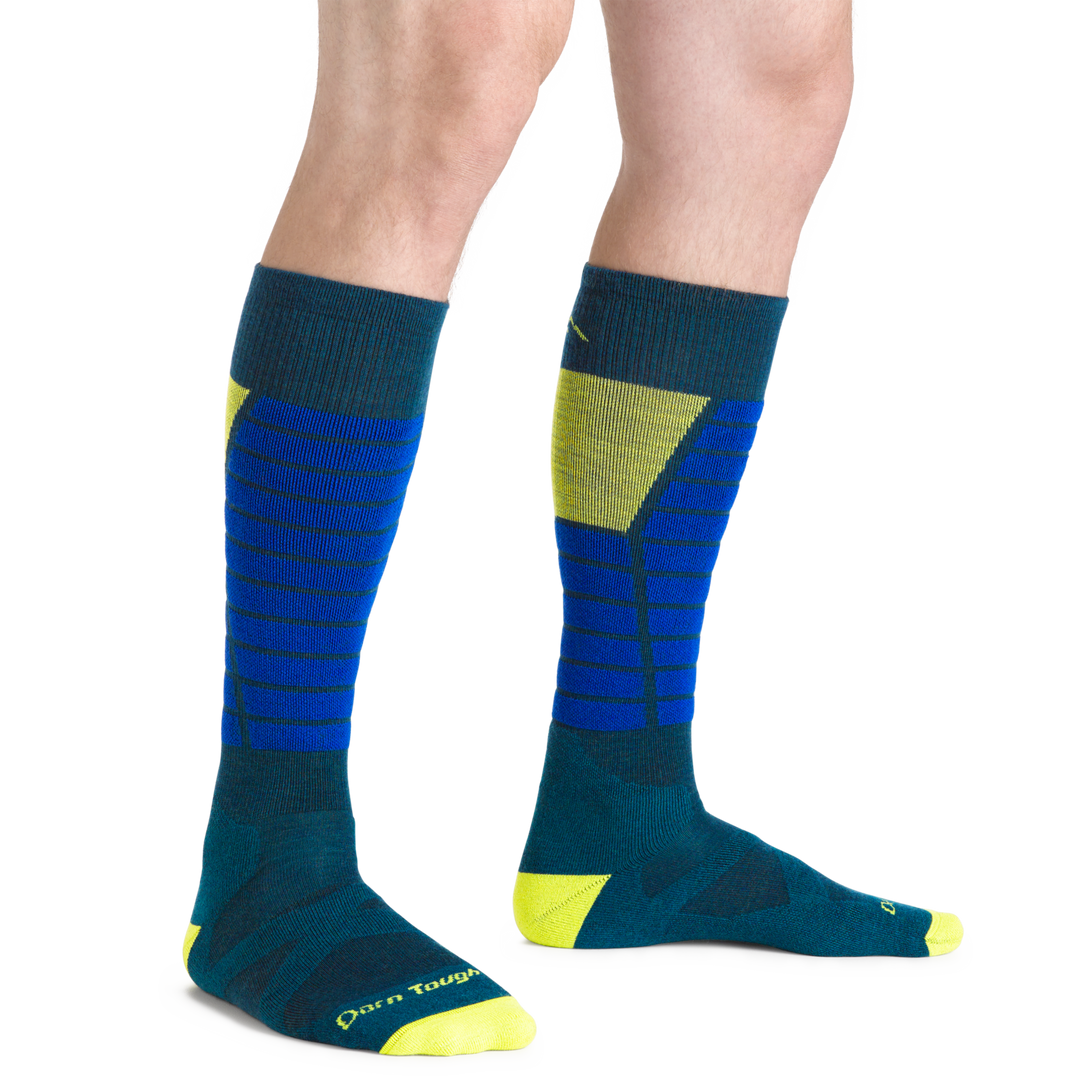 Man standing barefoot wearing Function X Over the Calf Ski & Snowboard socks in Dark Teal