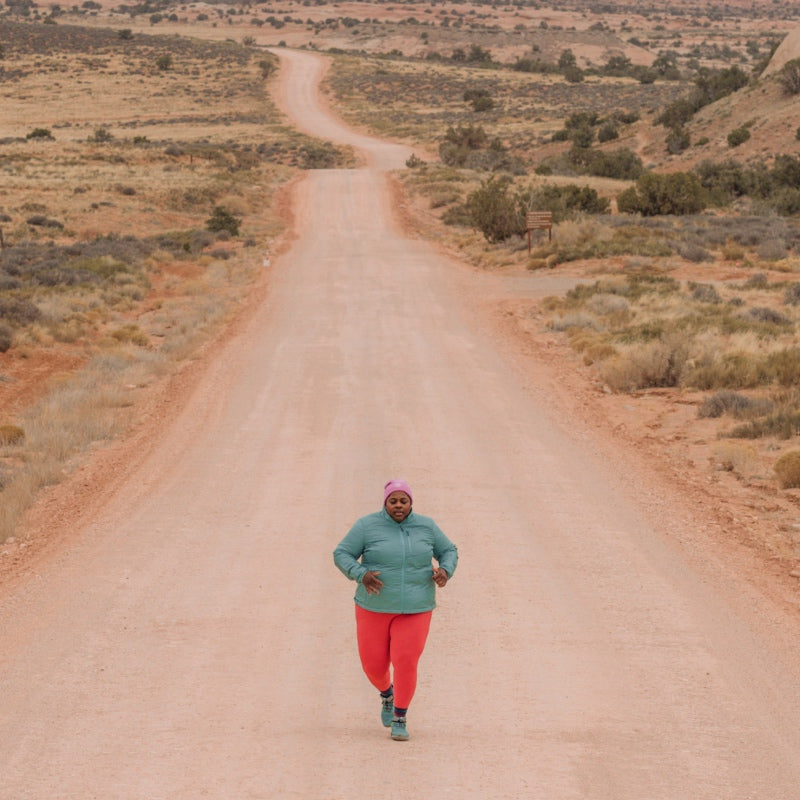 Mirna Valerio running down a dirt road out west wearing Darn Tough socks