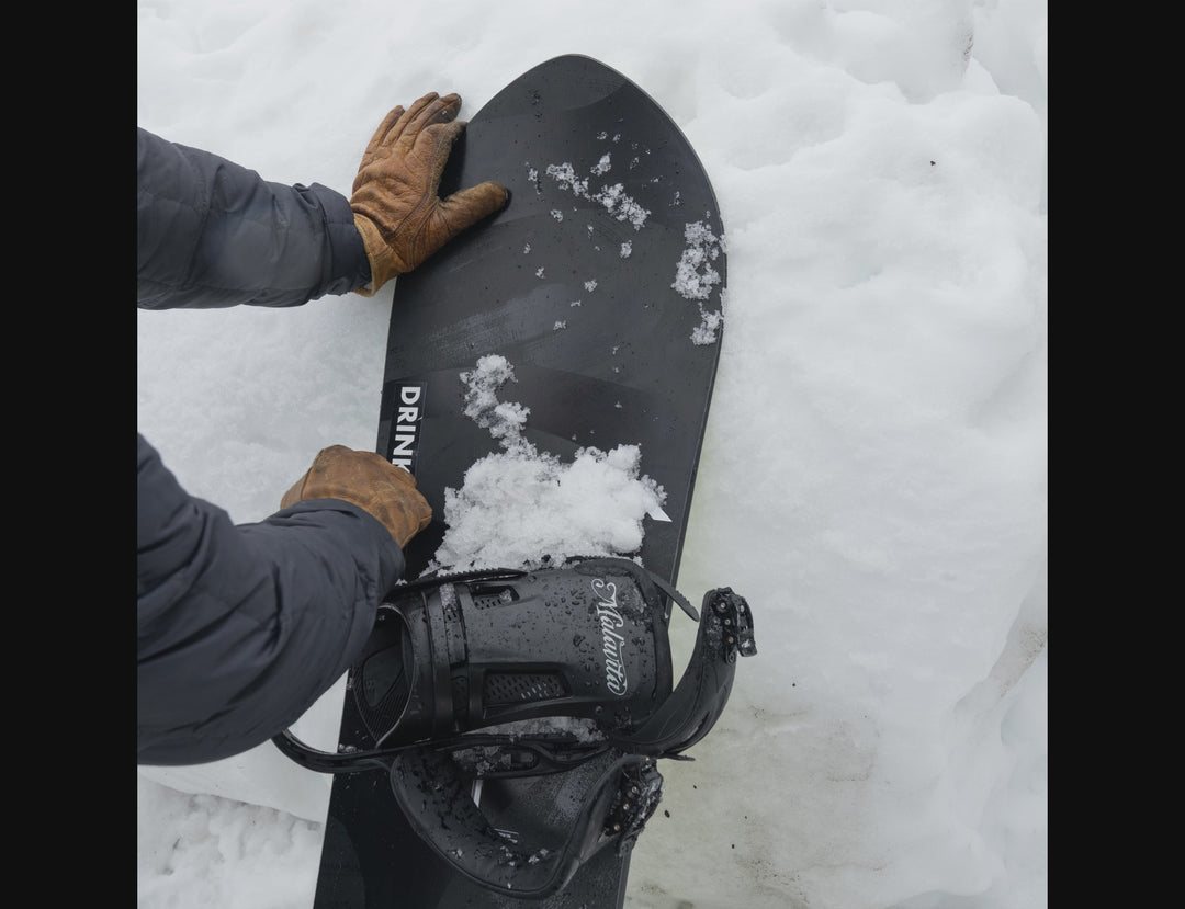 Video of snow being wiped off White Darn Tough mountain logo sticker on black snowboard