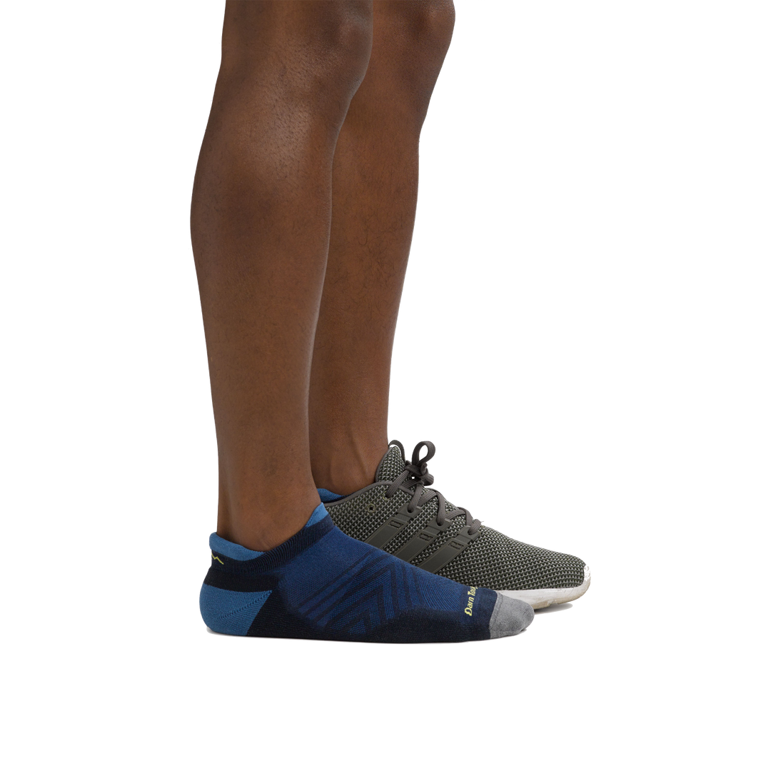 Side shot of model wearing the men's run no show tab running sock in eclipse blue with a gray sneaker on his left foot